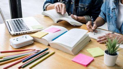 Two classmates in a library setting studying and reading together