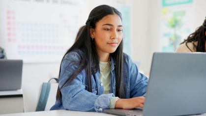 Teen looking at a laptop in a classroom