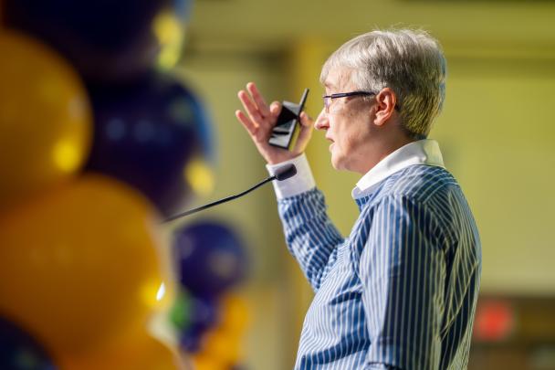 A person speaking into a mic standing next to balloons