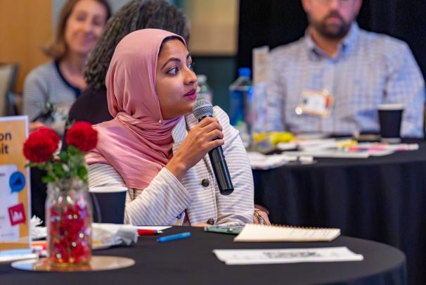 A seated audience member speaking into a microphone