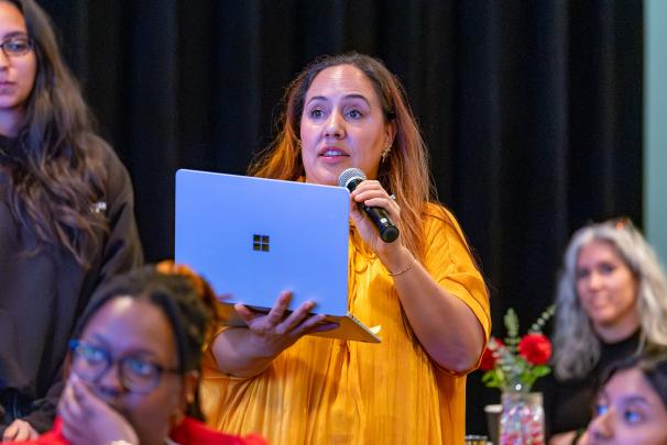 An audience member holding a laptop and speaking into a microphone