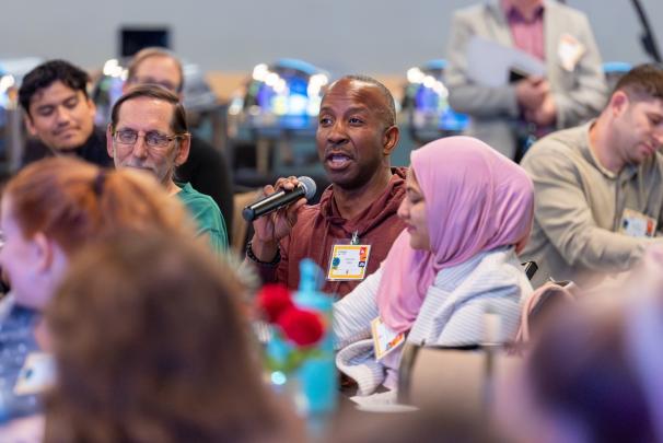 A seated audience member speaking into a microphone