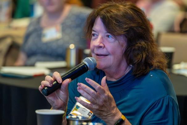 A seated audience member speaking into a microphone