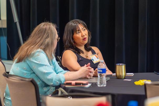 Two audience members chatting with each other at a table